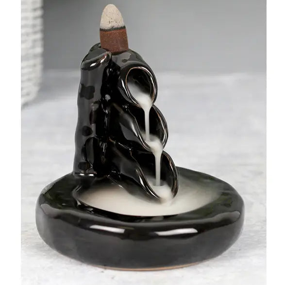 Black ceramic incense burner with white smoke on a light gray background