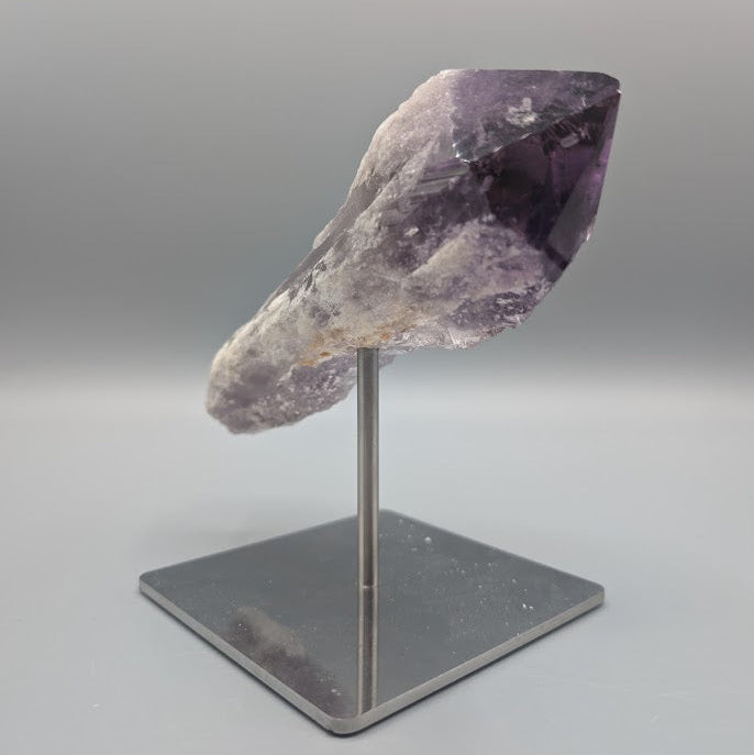 Amethyst crystal on a stand against a gray background