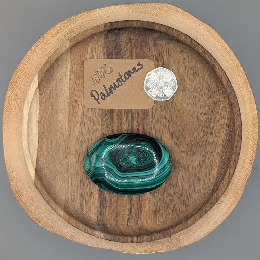 Malachite stone in a wooden display tray with a 'Palmtones' tag on a gray background