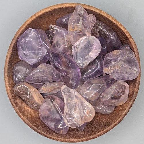 Brown bowl filled with ametrine tumblestones on a gray background