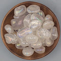 Brown bowl filled with angel aura quartz tumblestones on a gray background