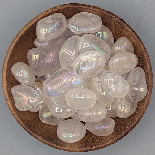 Brown bowl filled with angel aura quartz tumblestones on a gray background