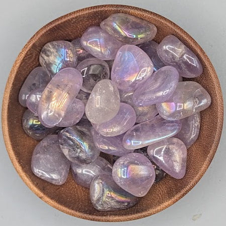 Wooden bowl filled with aura amethyst tumble stones on a grey background
