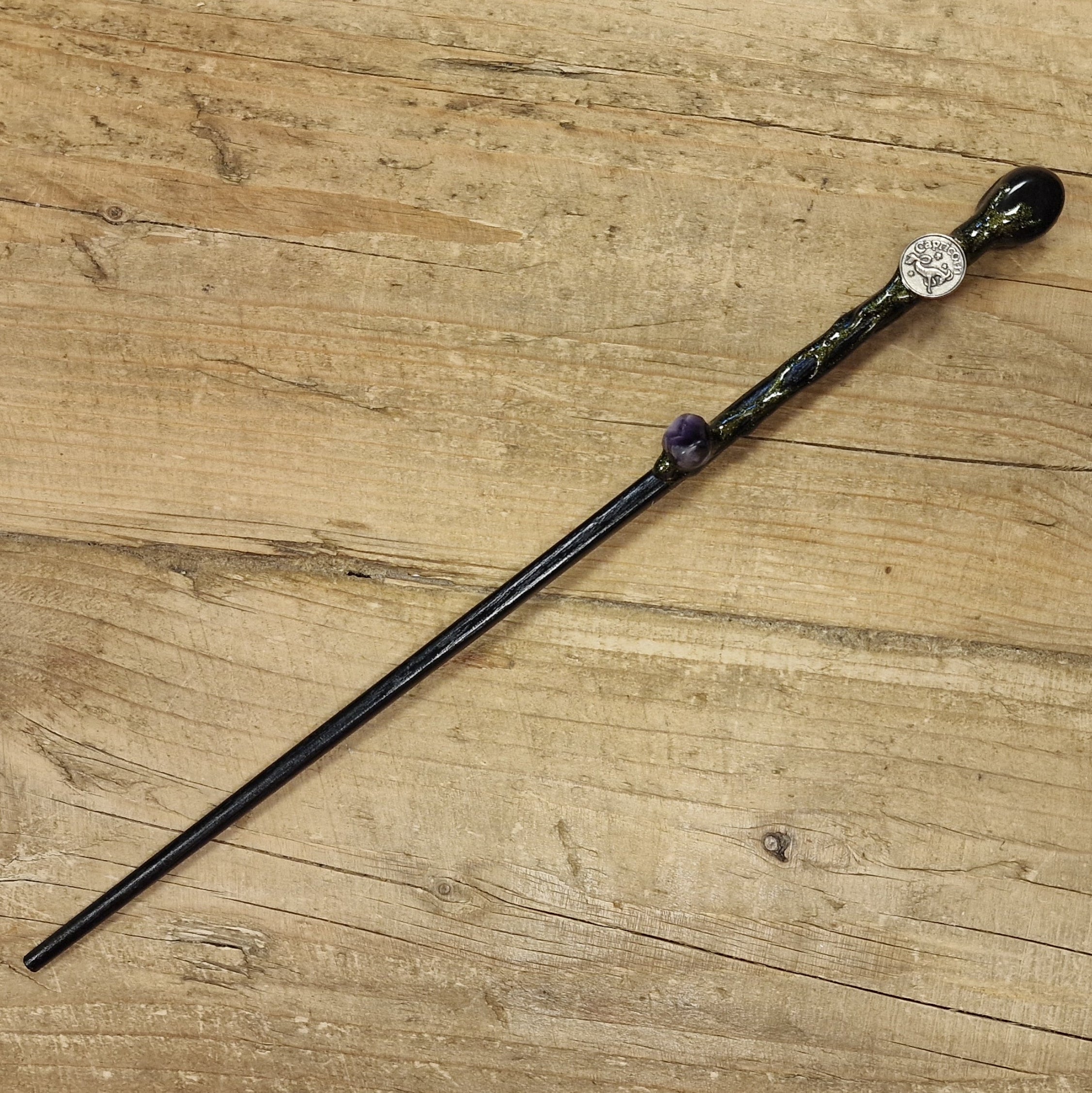 black wooden magic wand with Capricorn symbol