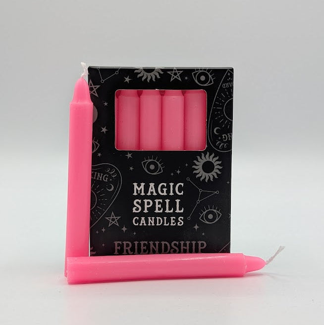 Pink candles with a 'Magic Spell Candles Friendship' packaging on a gray background