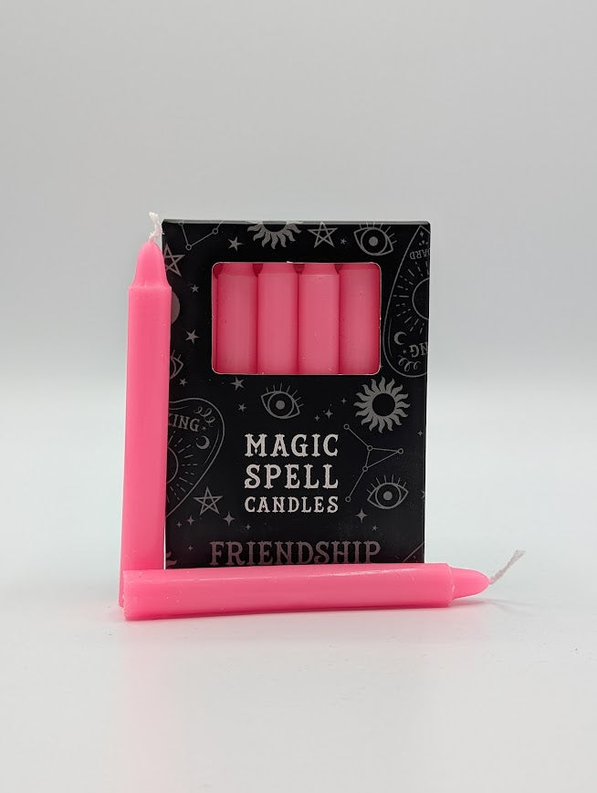 Pink candles with a 'Magic Spell Candles Friendship' packaging on a gray background