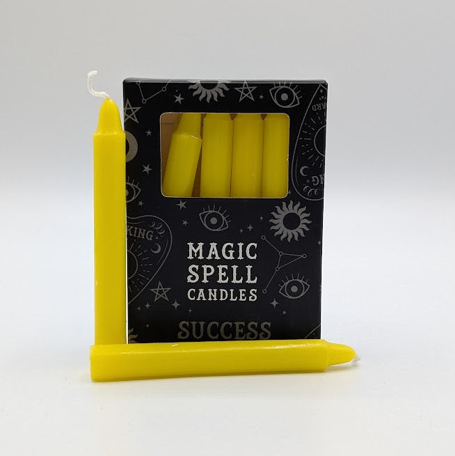 Yellow spell candles with packaging labeled 'Magic Spell Candles Success' on a white background