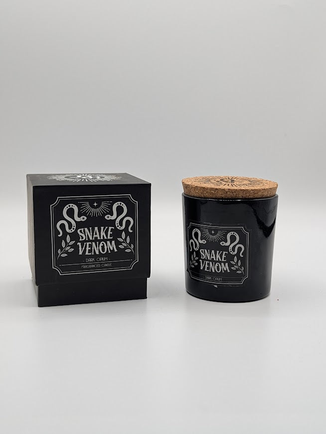 Black candle labeled 'Snake Venom' dark opium scented with a matching black box on a white background