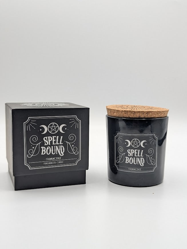 Black candle with cork lid and packaging labeled 'Spell Bound' frankincense on a white background