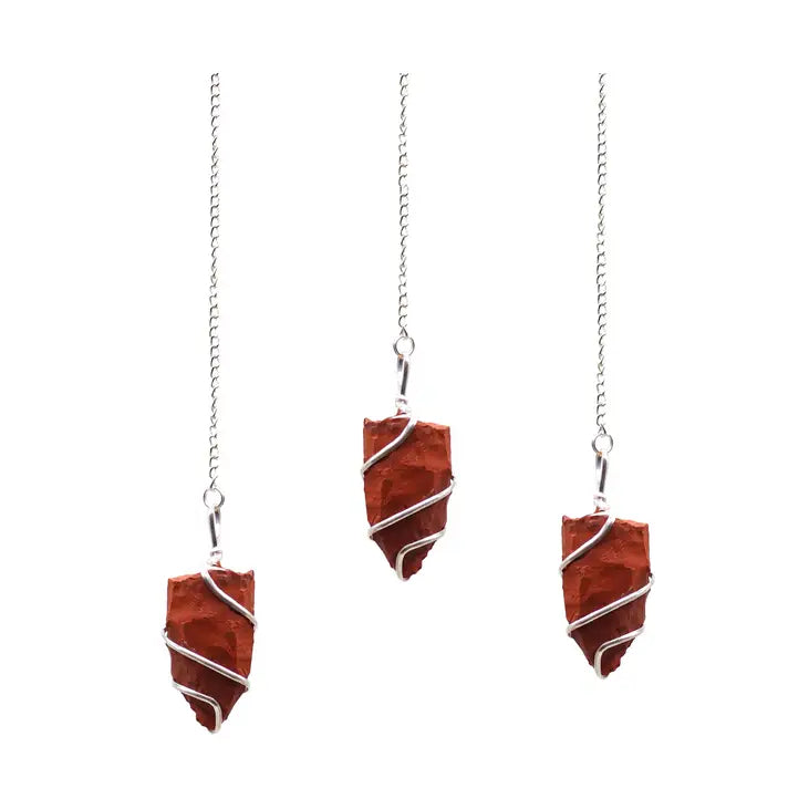 Three red stone pendulums on silver chains against a white background