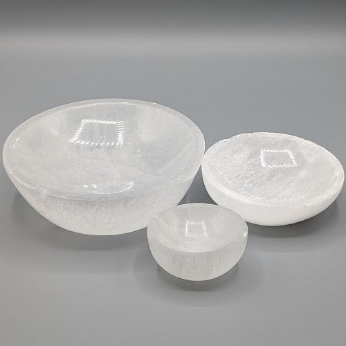 Three white selenite dishes in different sizes on a grey background