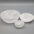 Three white selenite dishes in different sizes on a grey background