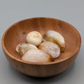 Wooden bowl filled with synthetic citrine tumble stones on a grey background